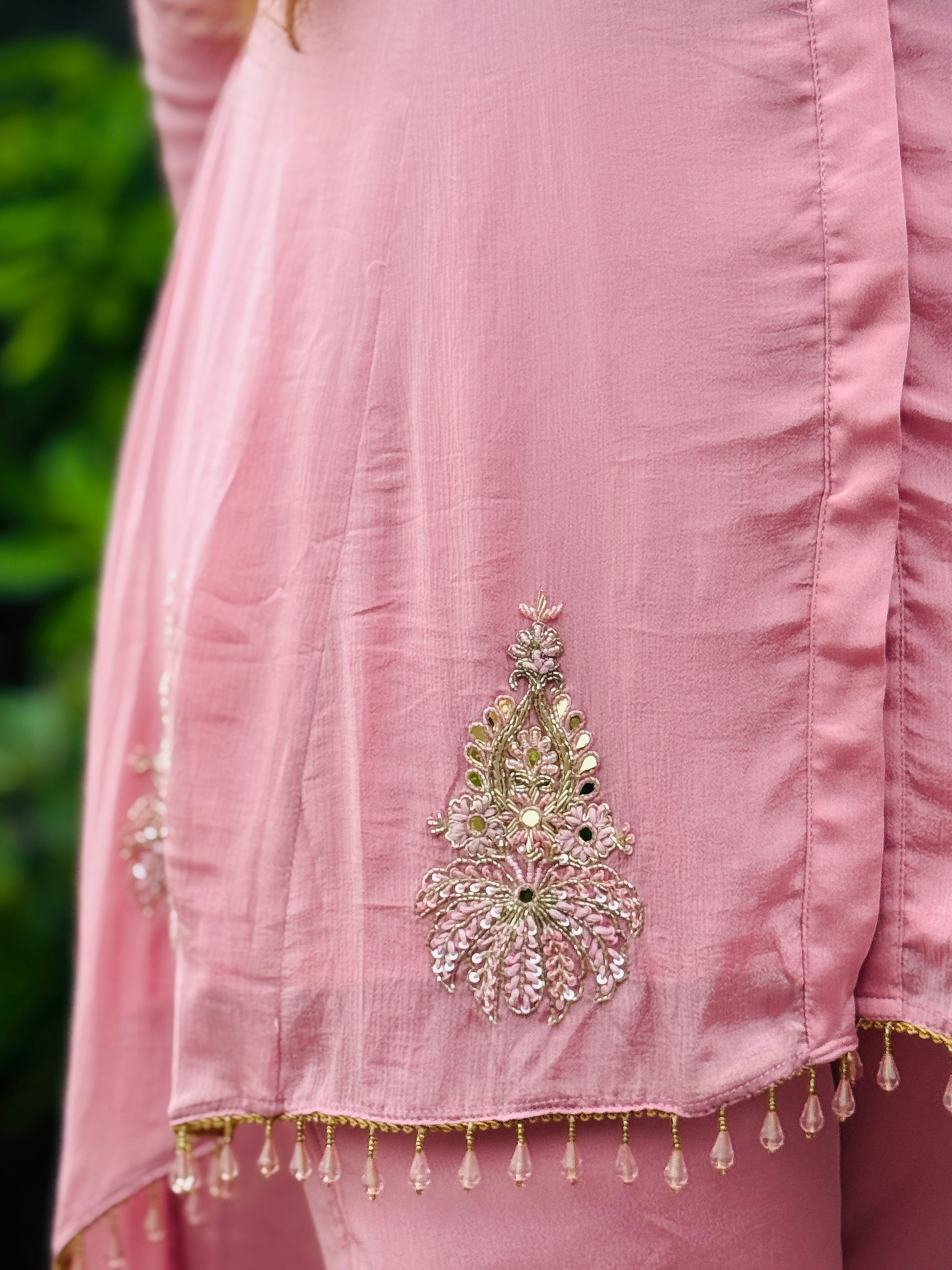 Close-up of a pink traditional outfit with intricate embroidery and embellishments.